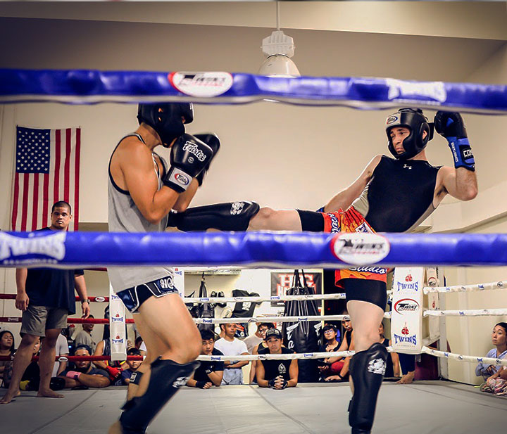 Intense Muay Thai sparring captured with Fight-Ring-Snap, showcasing powerful kicks and defensive techniques in a professional ring.